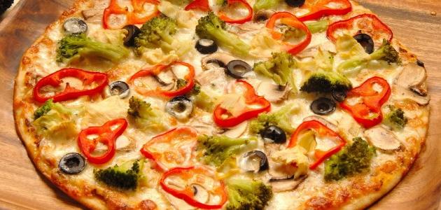 Spread pizza dough on a floured surface to medium thickness. 2. Transfer the dough to an oiled tray and poke holes in the dough with a fork. 3. Spread the pizza sauce over the dough, avoiding the edges of the dough. 4. Distribute green peppers, tomatoes, onions, mushrooms, olives and herbs. 5. Drizzle olive oil on top. 6. Put the pizza in the oven at 160 degrees for 15 minutes. 7. Take out the tray and spread the grated mozzarella cheese over it and return it to the oven for an additional 10-15 minutes until it is brown and the cheese melts. 8. Cut the pizza and serve it hot.